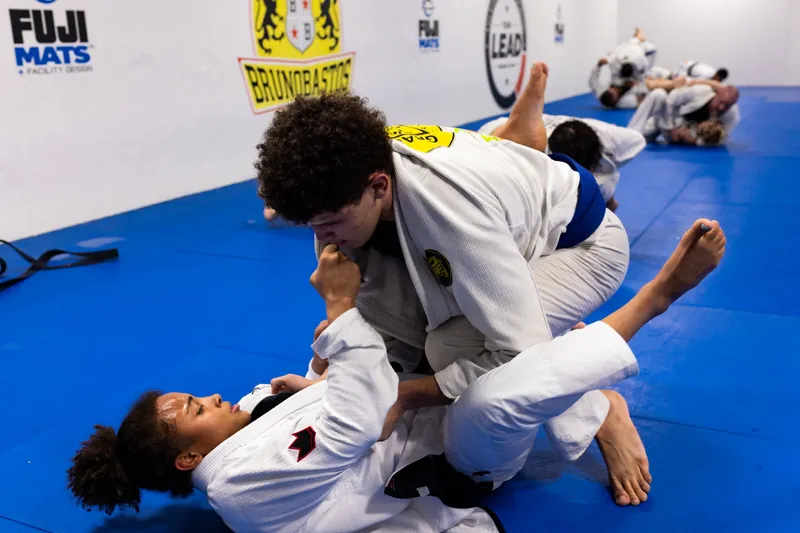 Adults rolling at Bastos BJJ Midland — live training with the Bruno Bastos academy banner visible