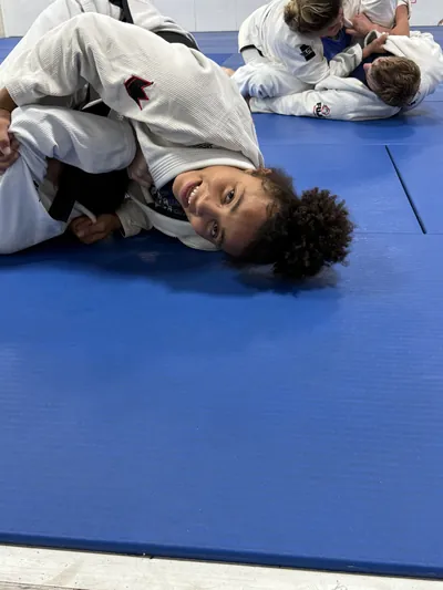 Bastos BJJ student smiling on the blue mats — joyful training moment in Midland Texas